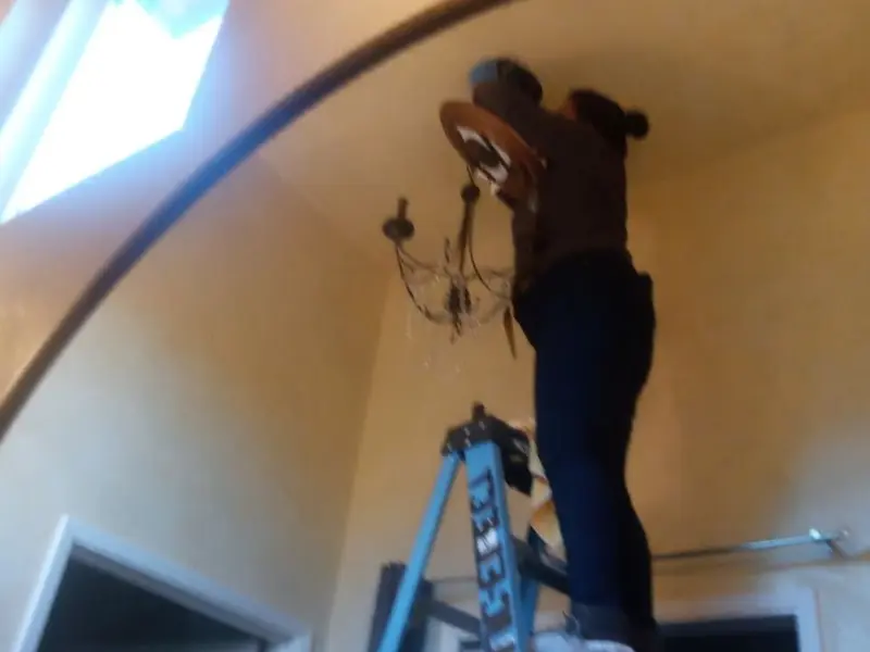 Electrician installing a chandelier in a Glasgow residence